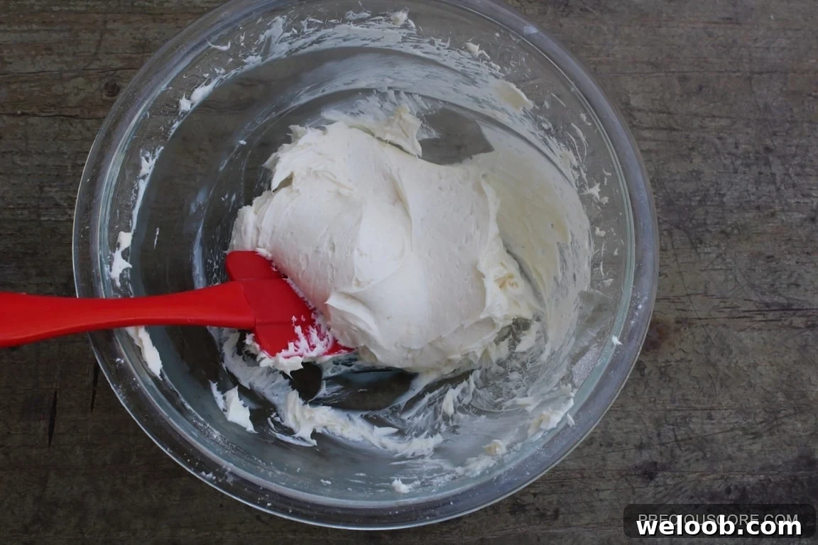 Red spatula mixing cream cheese filling ingredients.