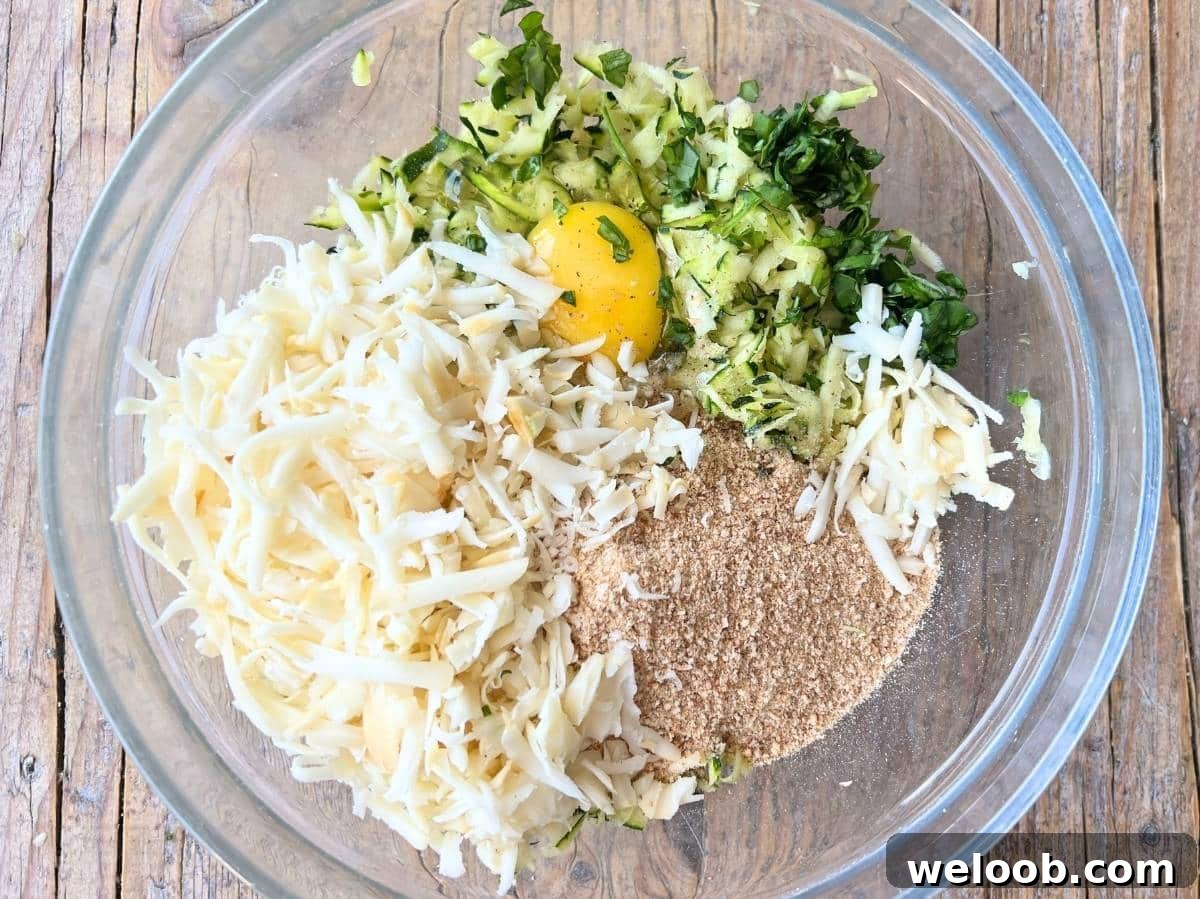 Egg, zucchini, breadcrumbs, cheese, nutmeg, garlic and basil in a mixing bowl.