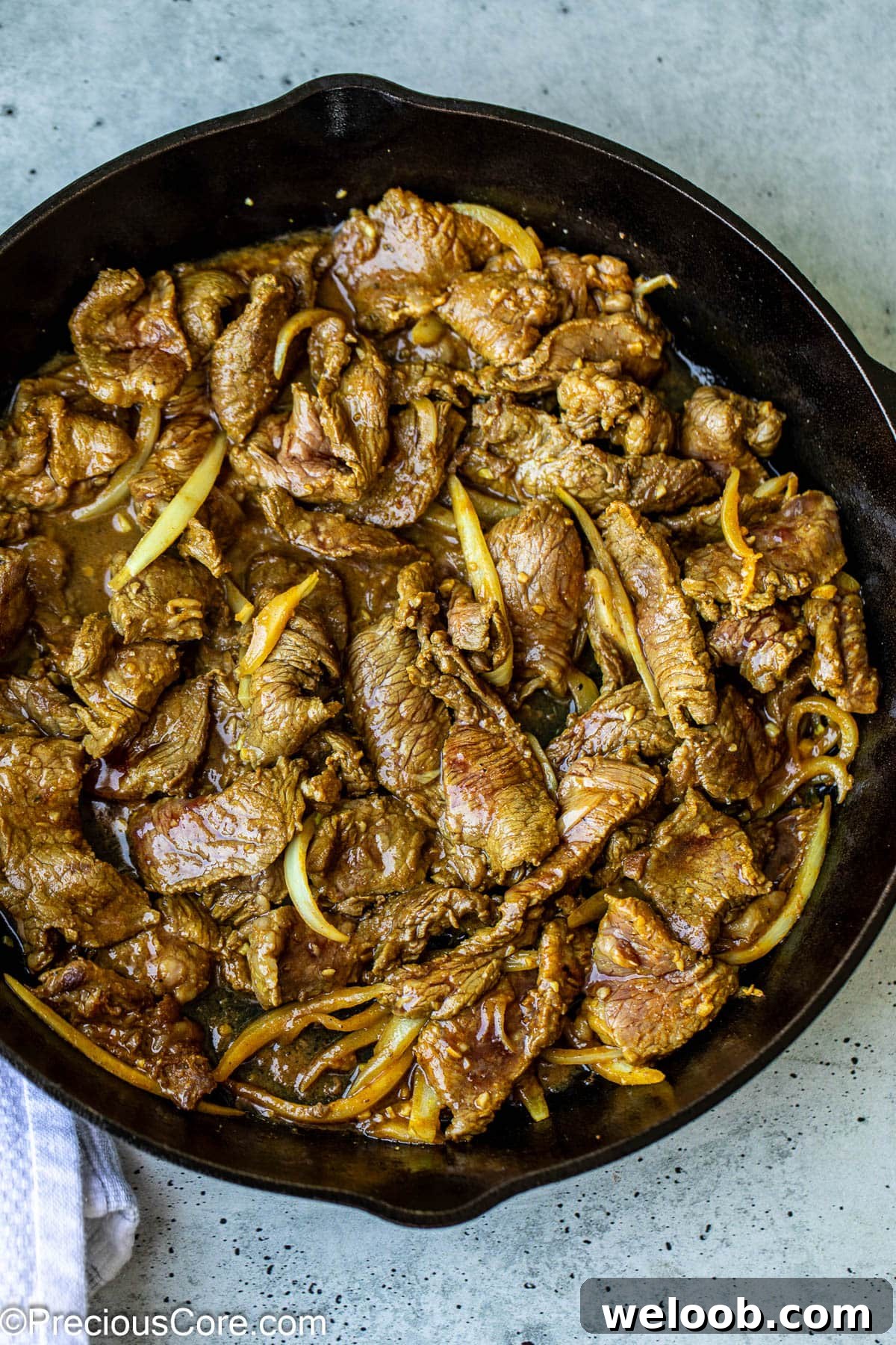 Cooking marinated beef shawarma in a skillet.