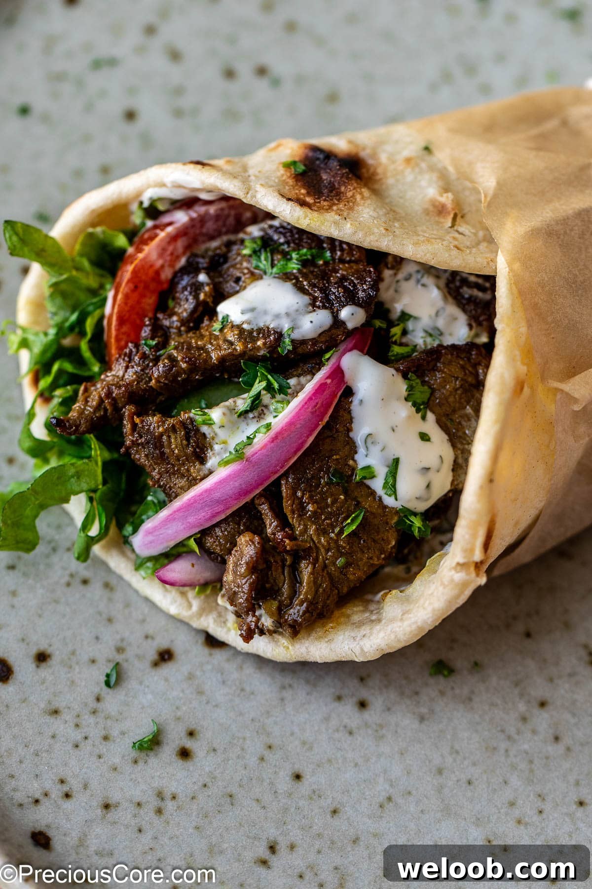 Beef shawarma wrap with veggies and sauce.