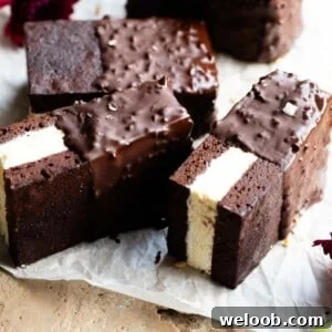 Three ice cream sandwiches with a chocolate sponge and vanilla ice cream sitting on their sides on some baking parchment.