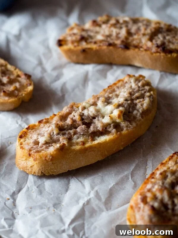This two ingredient stracchino and sausage crostini is so simple and crazy delicious. Tangy, soft cheese is mixed with Italian sausage and spread on some thick crusty bread. An easy sausage crostini recipe you're sure to love. More authentic italian recipes at Insidetherustickitchen.com