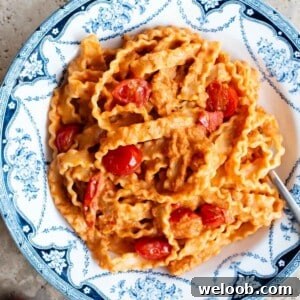 Pasta ribbons in a creamy sundried tomato sauce in a blue and white bowl.