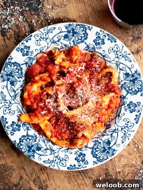 Trippa Finta (Italian omelette in tomato sauce) in a blue and white bowl sitting on a wooden surface.