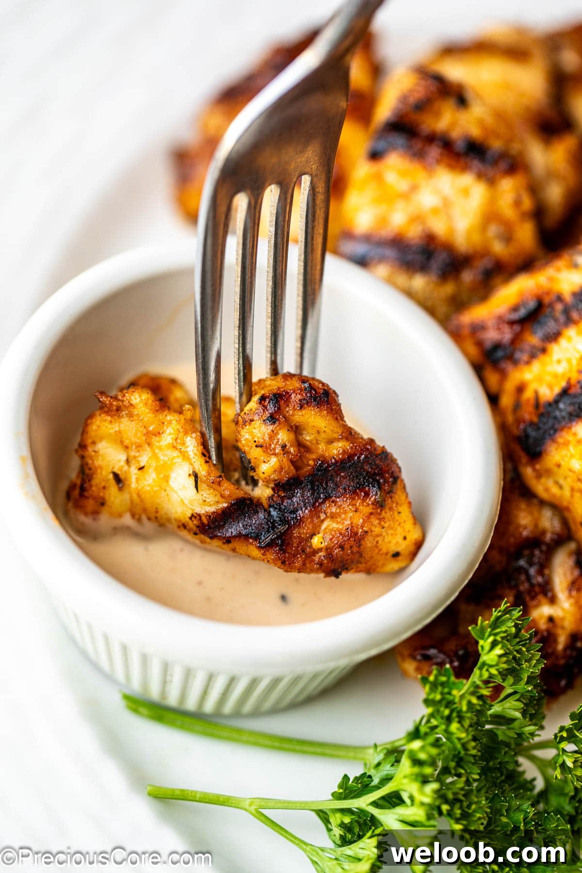 Dipping grilled chicken nuggets in sauce.