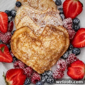 Heart shaped pancakes on a plate with berries.