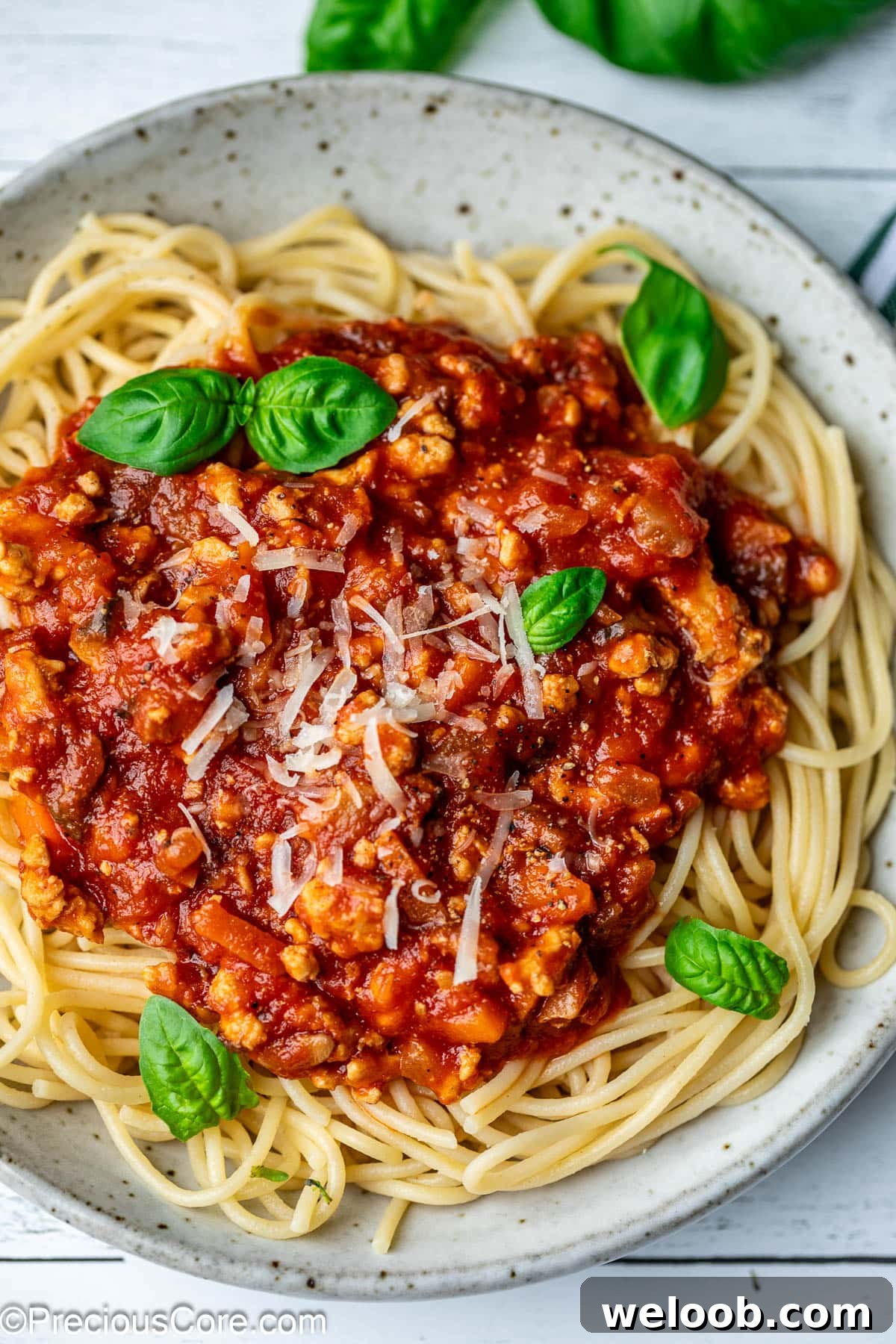 Spaghetti in a bowl topped with chicken Bolognese sauce.