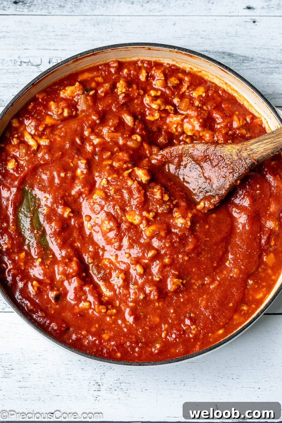 A pot of vibrant red sauce made with chicken.
