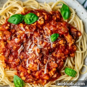 Spaghetti in a bowl topped with chicken Bolognese sauce.