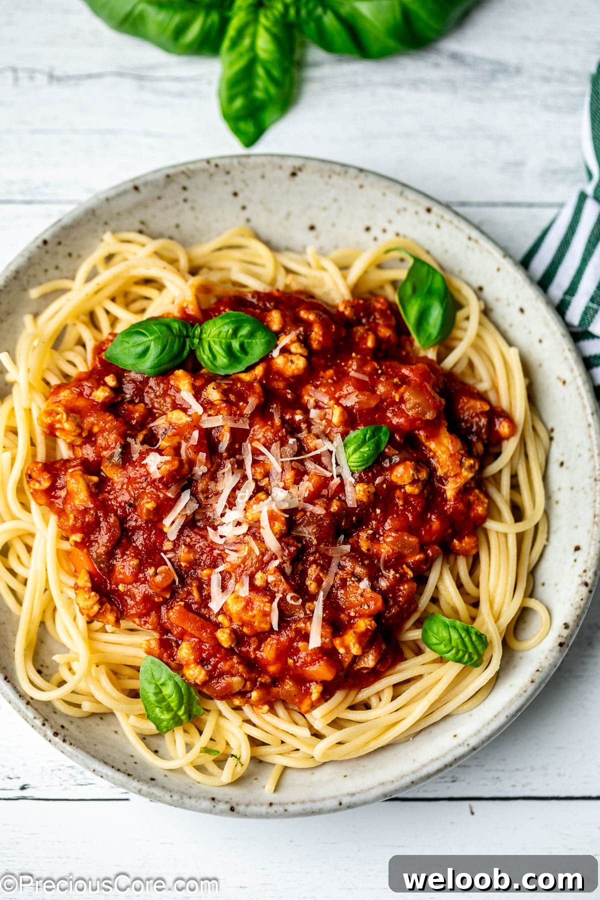 Spaghetti Bolognese Chicken in a bowl topped with shredded parmesan cheese.