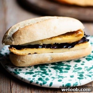 A close up of a roll filled with a chickpea flatbread and marinated eggplant.