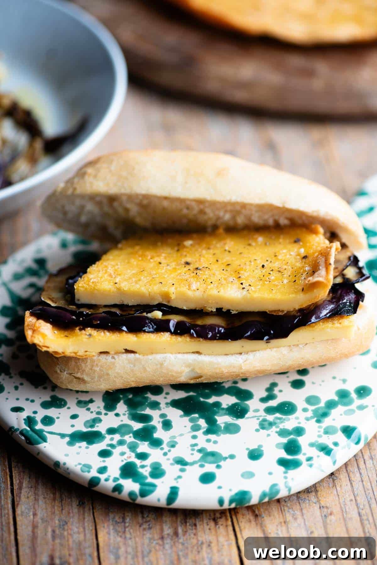 An open view of a 5x5 sandwich filled with a chickpea flatbread and eggplant.