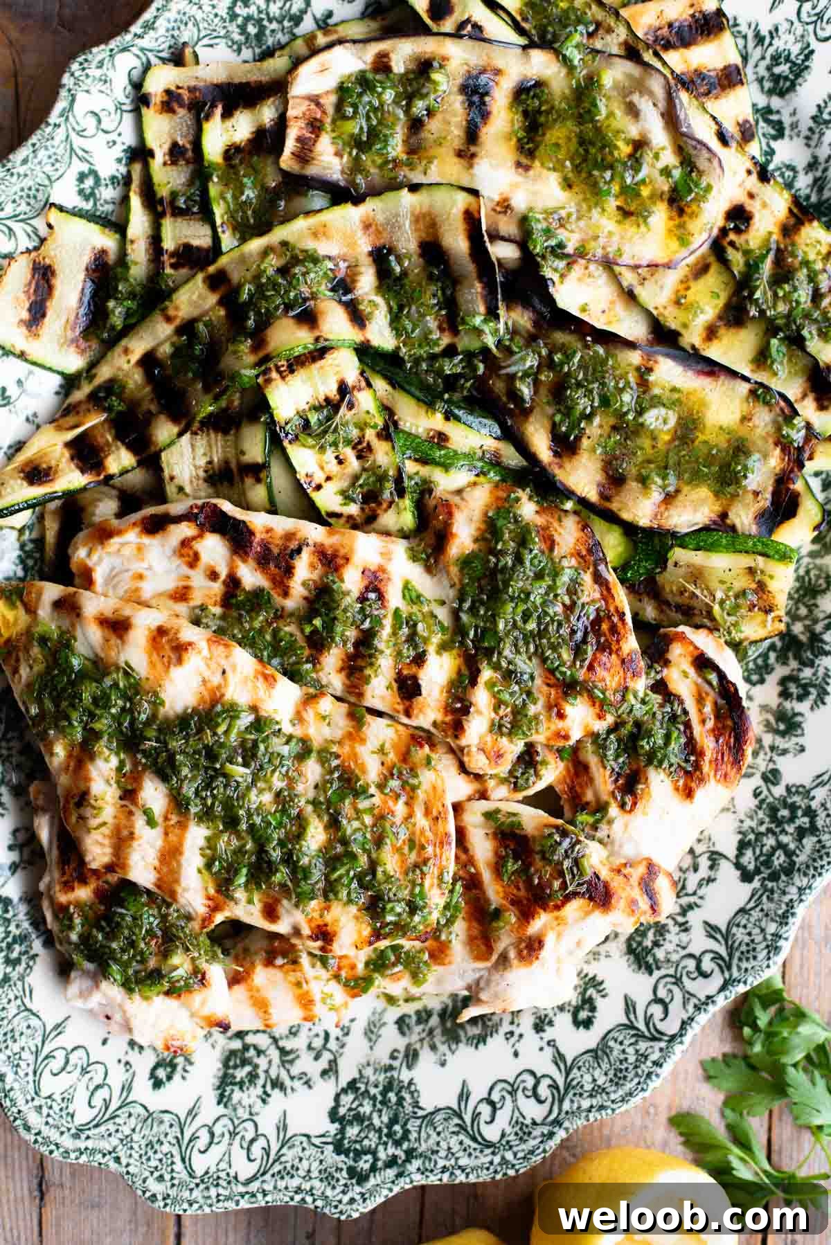 Grilled chicken and vegetables on a platter with Salmoriglio sauce over the top.