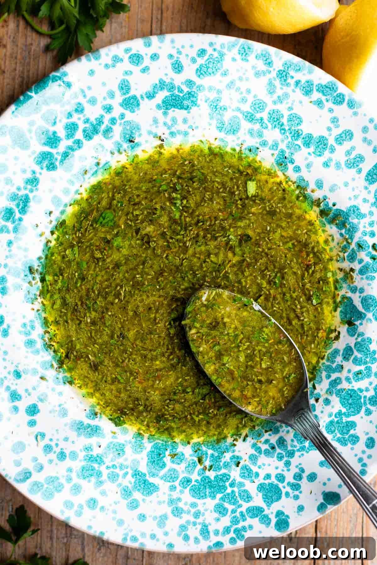 Salmoriglio sauce in a green splatter pattern bowl with a spoon.