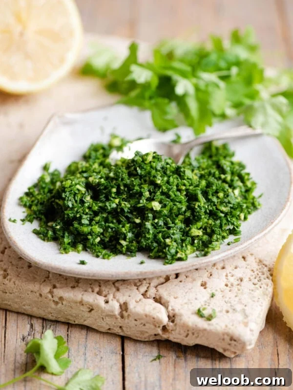 Gremolata on a small plate with wedges of lemon and parsley in the background