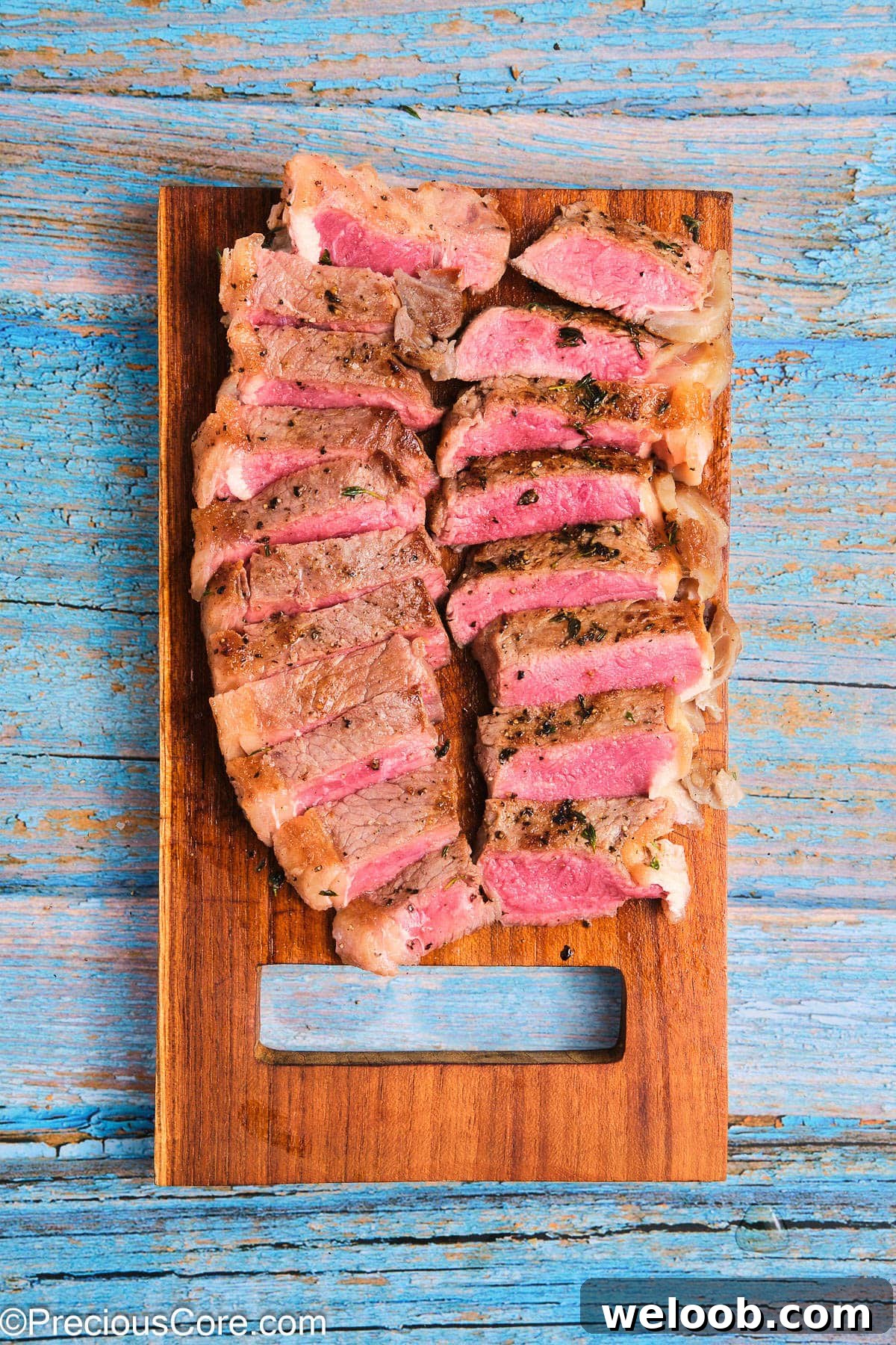 Cooked sliced ribeye steak on a chopping board.