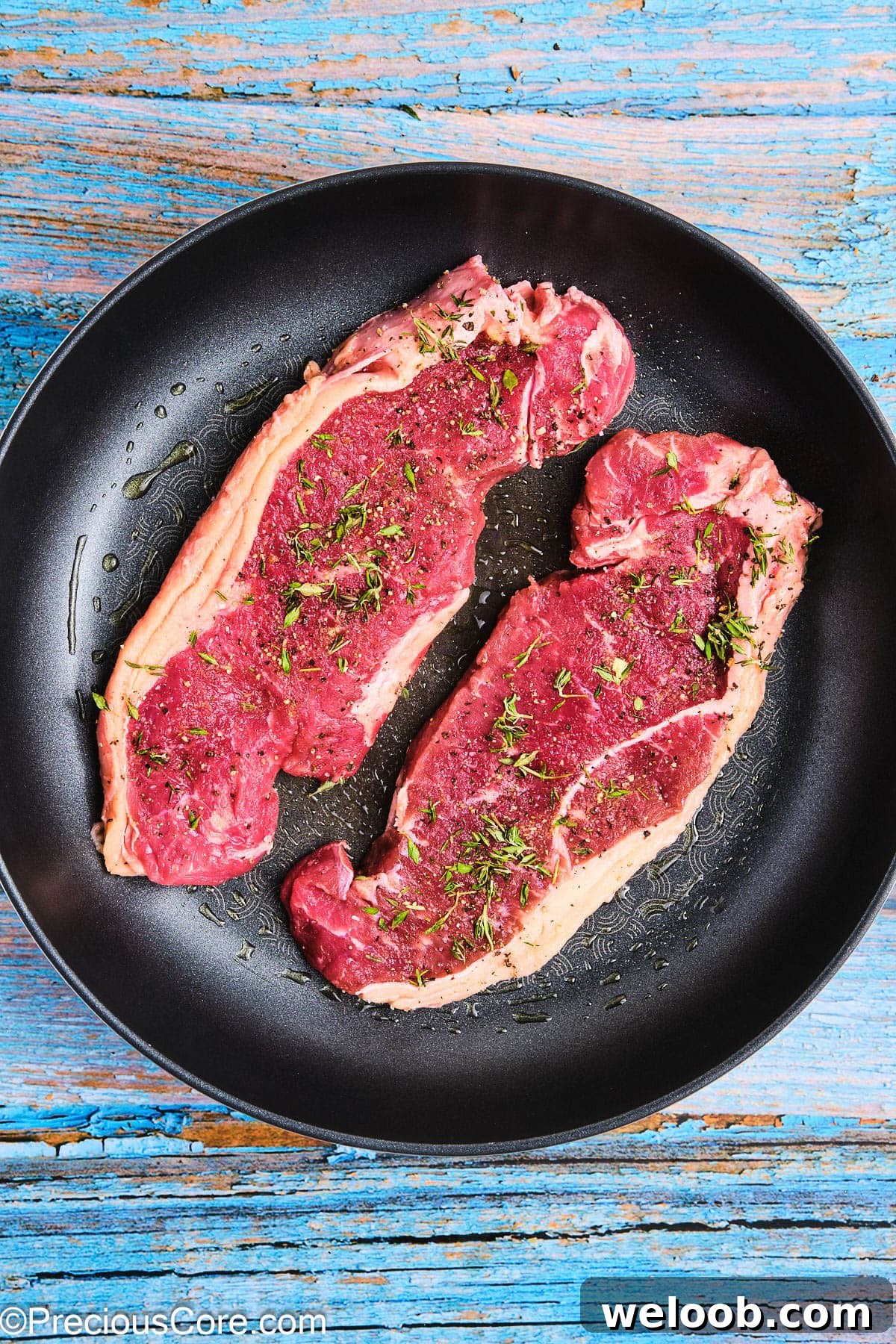 Seasoned steaks in a non-stick skillet.