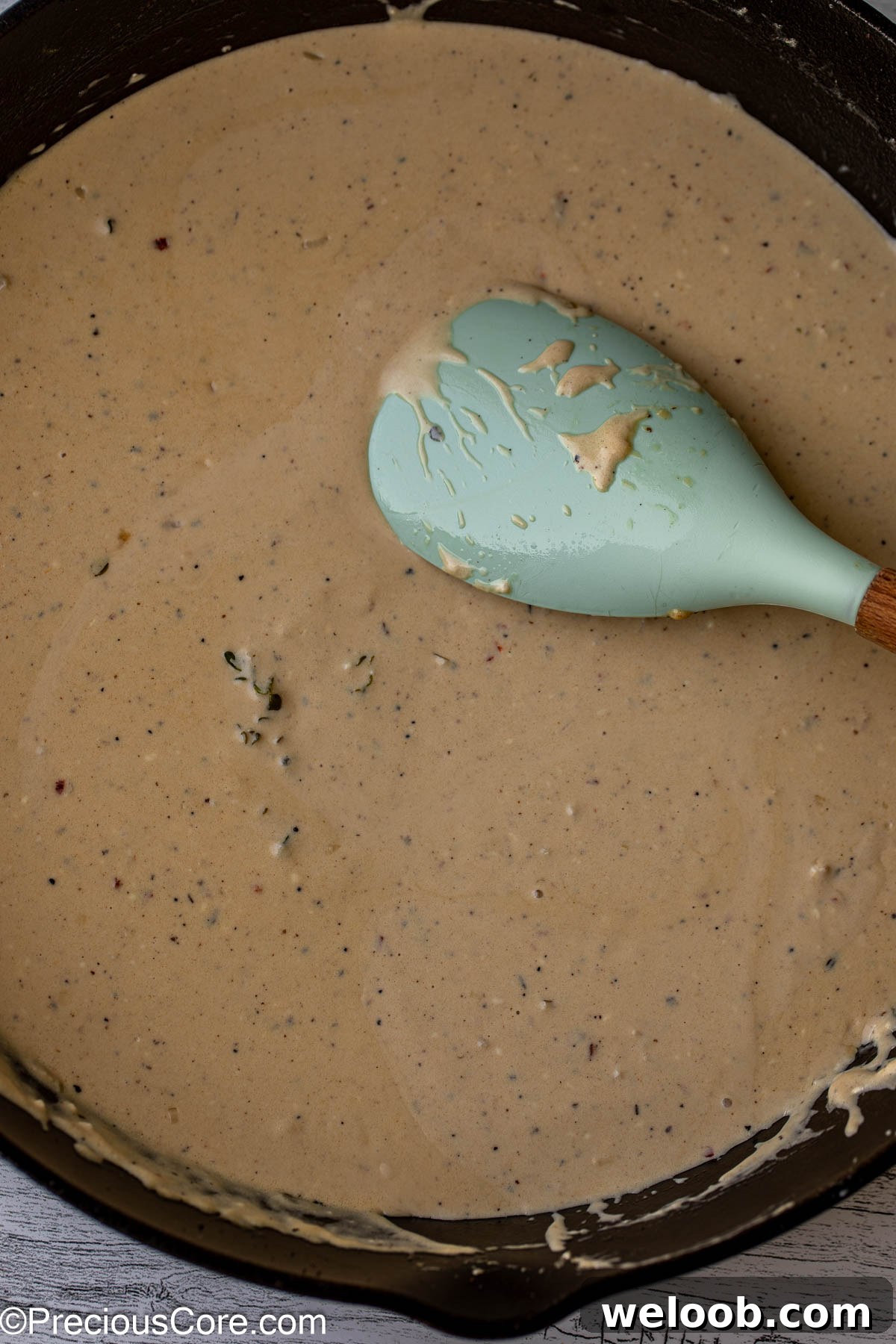 Stirring homemade cream sauce with a large spoon.