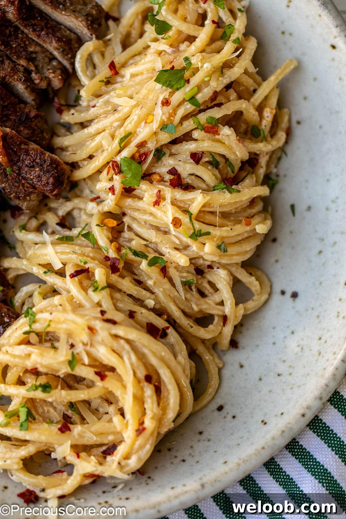 Steak and Pasta dinner served with red pepper flakes.