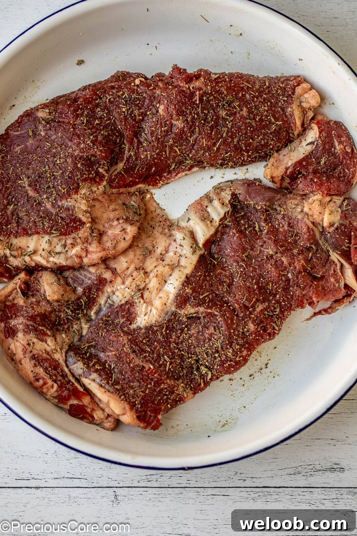 Raw seasoned ribeye steaks.