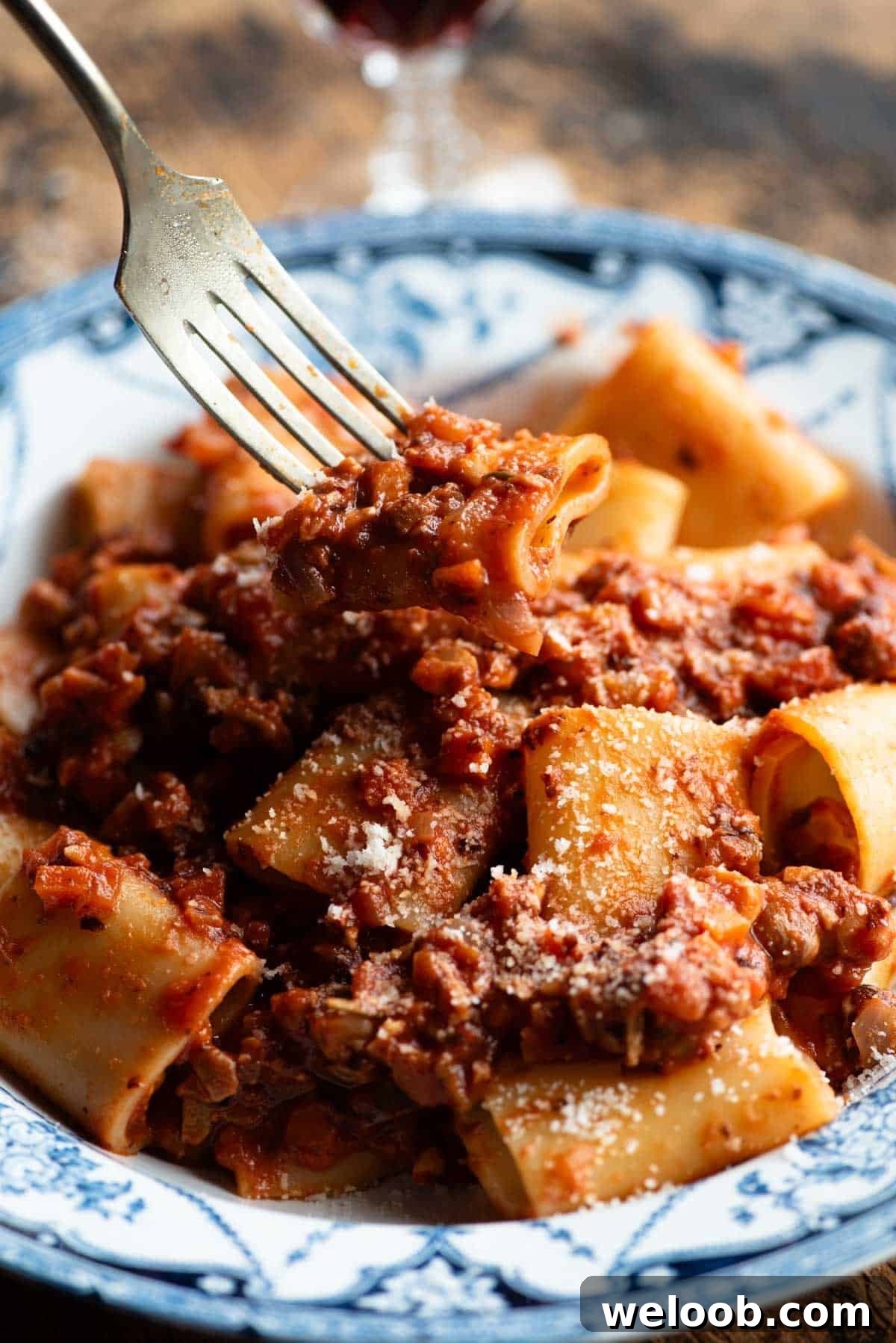 A close up of a fork holding a piece of pasta with hazelnut ragu over a bowl.
