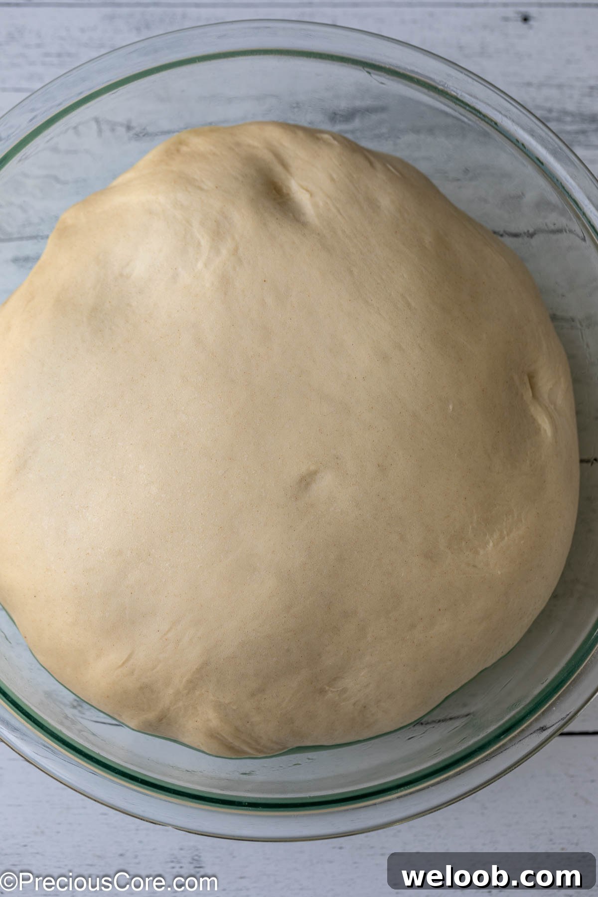 Risen cinnamon roll dough in a bowl.