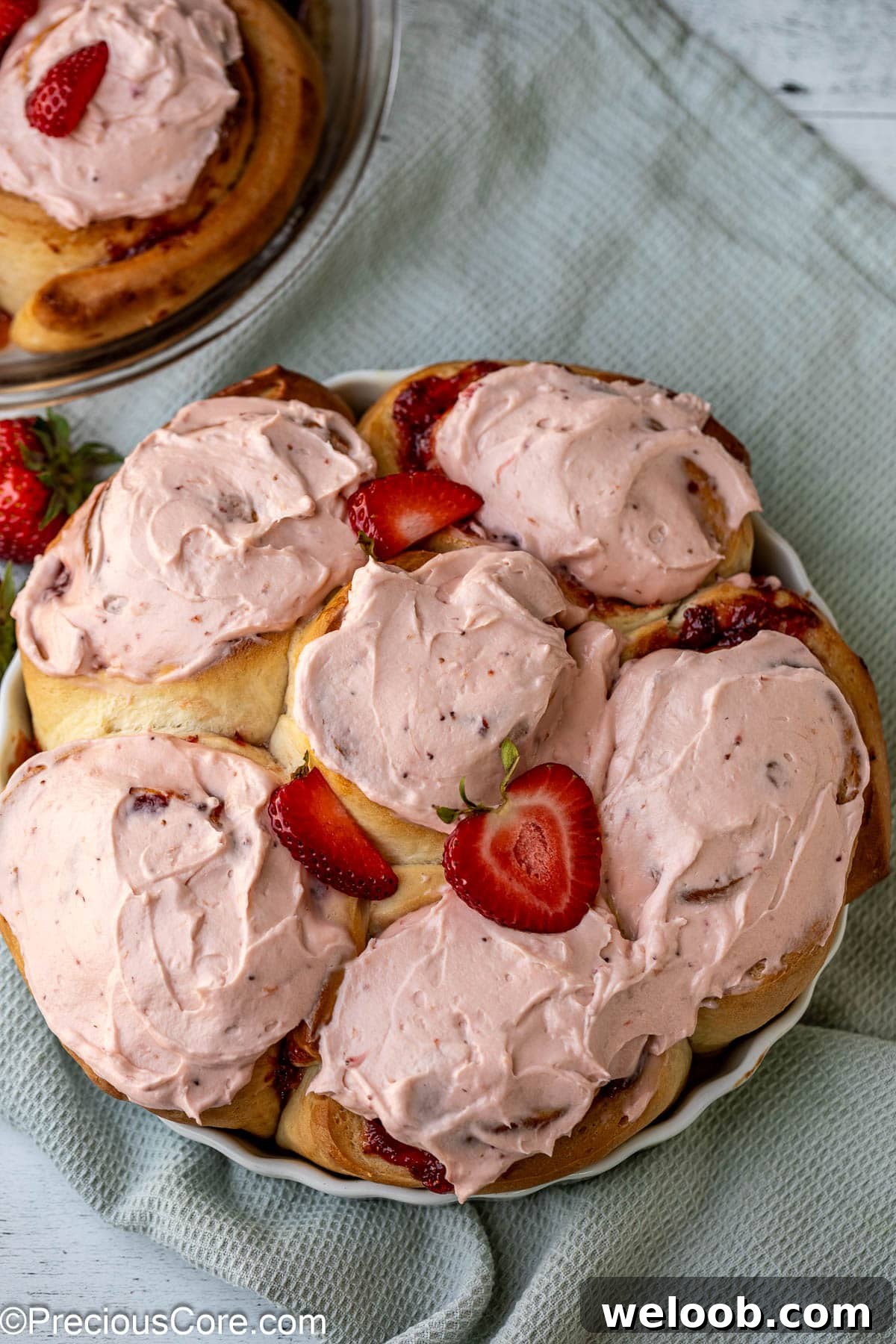 Frosted strawberry cinnamon rolls in round baking dish.