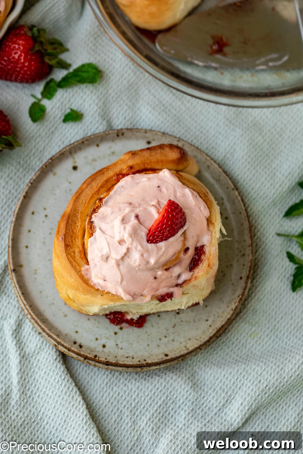 A strawberry cinnamon roll on a dessert plate.