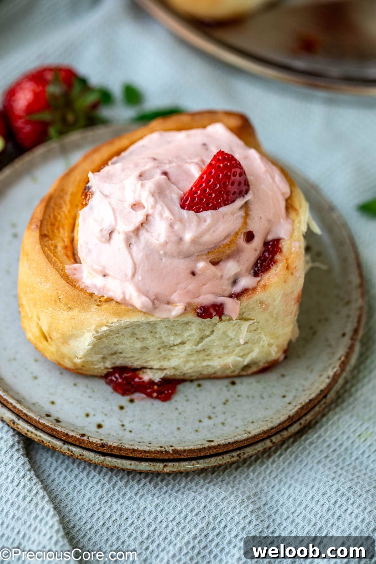 Strawberry cinnamon roll with fresh strawberry garnish.