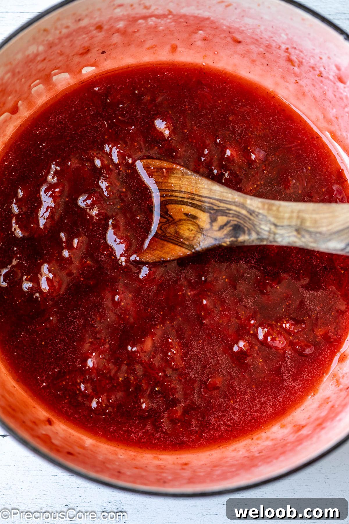 Mixing strawberry compote with a wooden spoon.