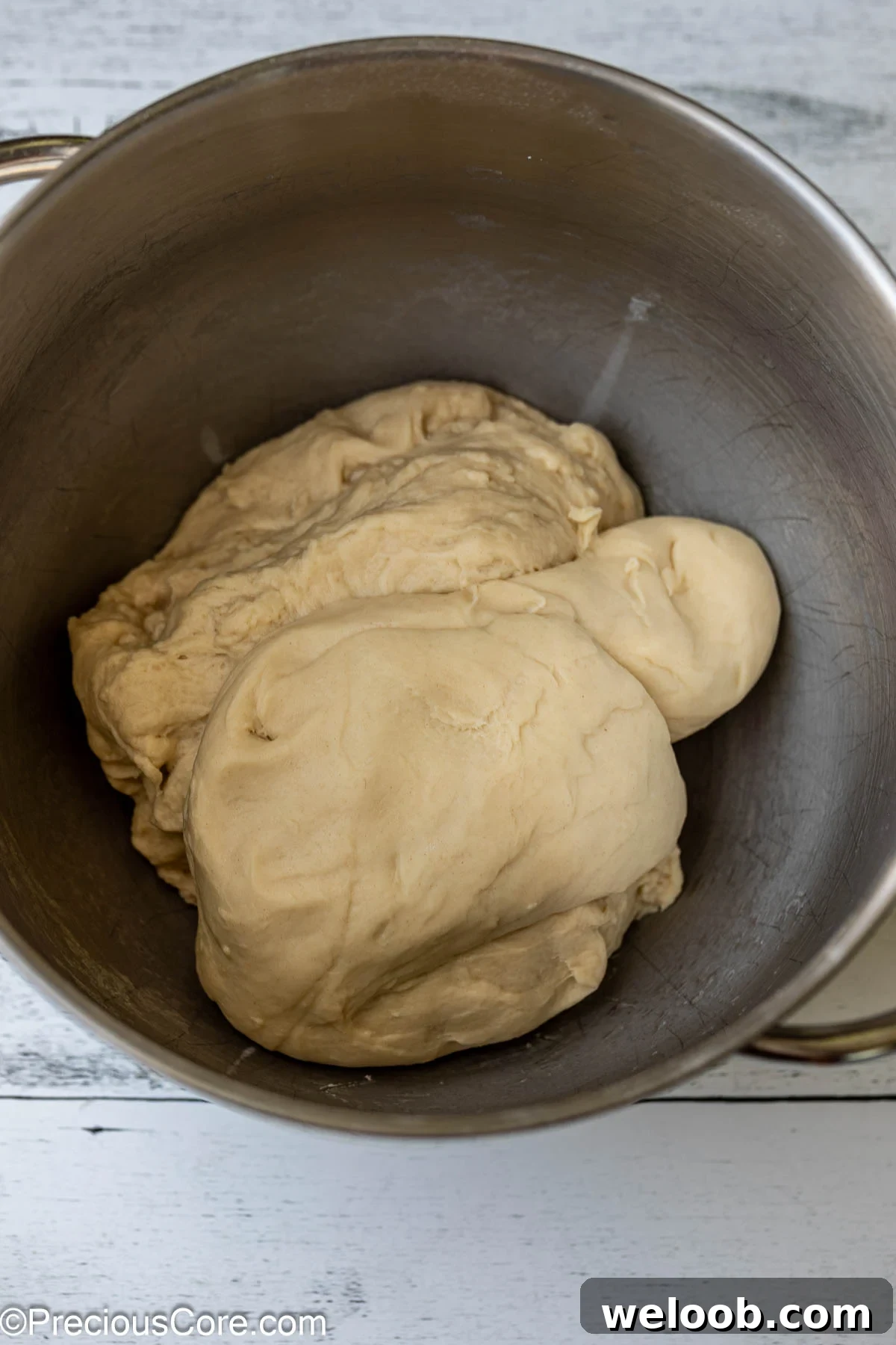 Soft cinnamon roll dough in a metal bowl.