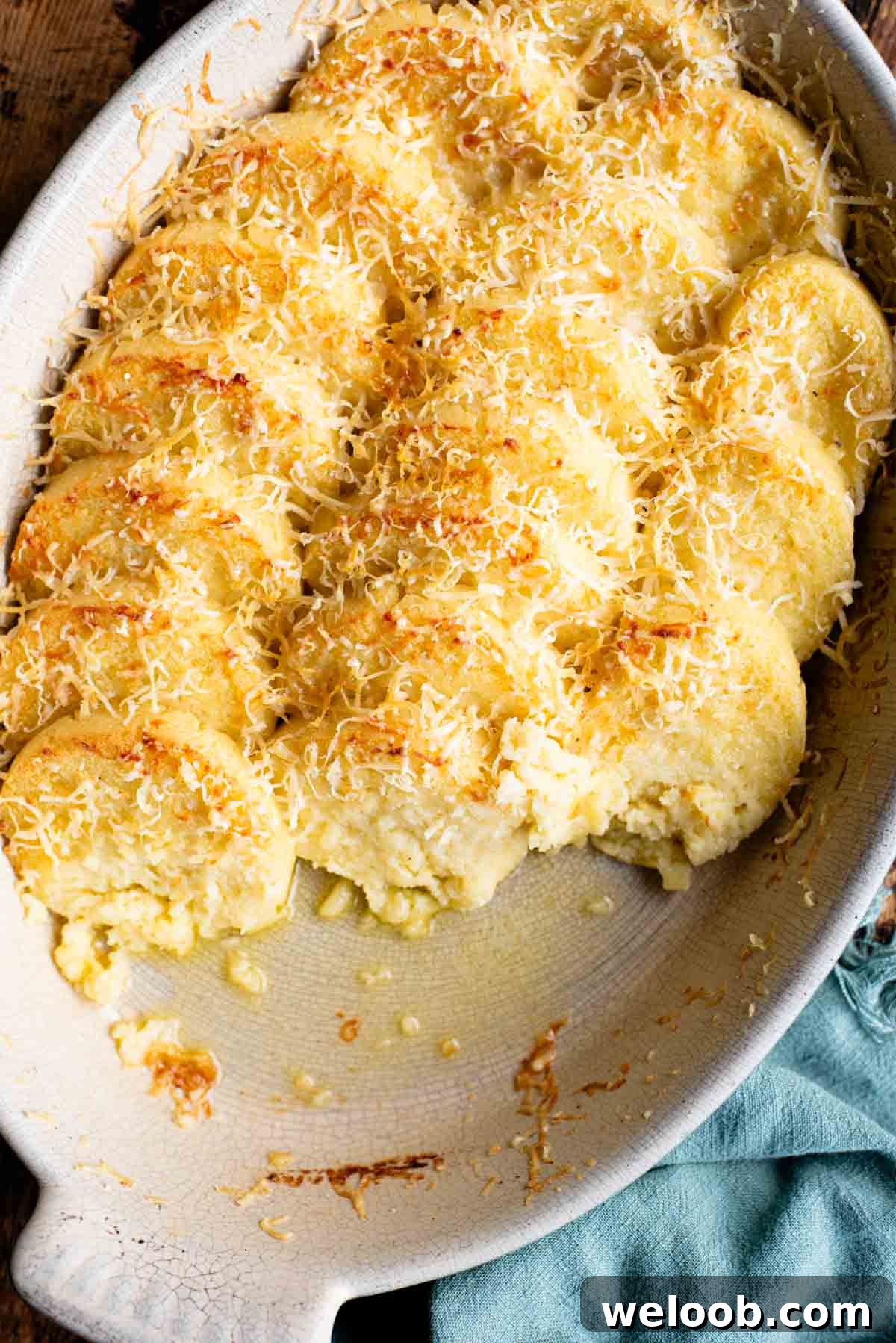 A close up of Gnocchi alla Romana in a baking dish with some removed showing the buttery dish.