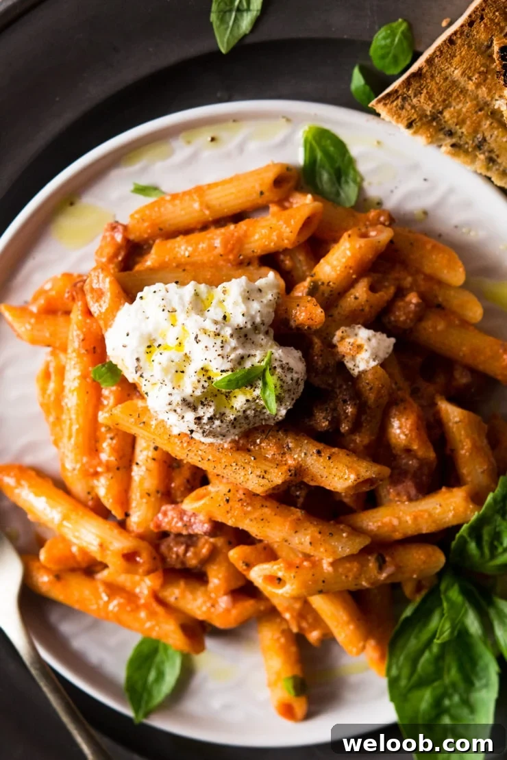 A close up of pasta with pancetta topped with a dollop of ricotta cheese