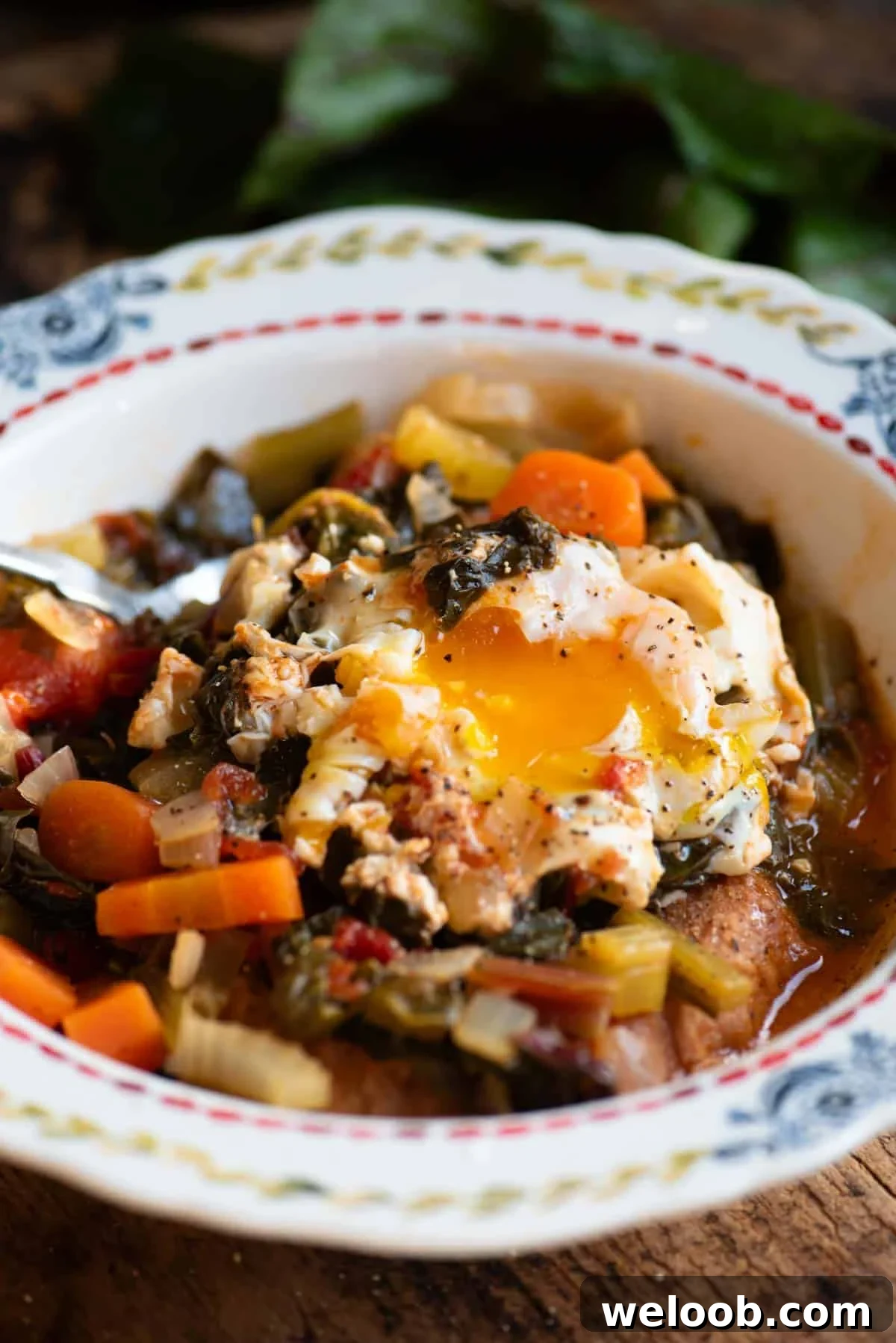 A close up of a Tuscan vegetable soup (Acquacotta) in a bowl topped with a poached egg.