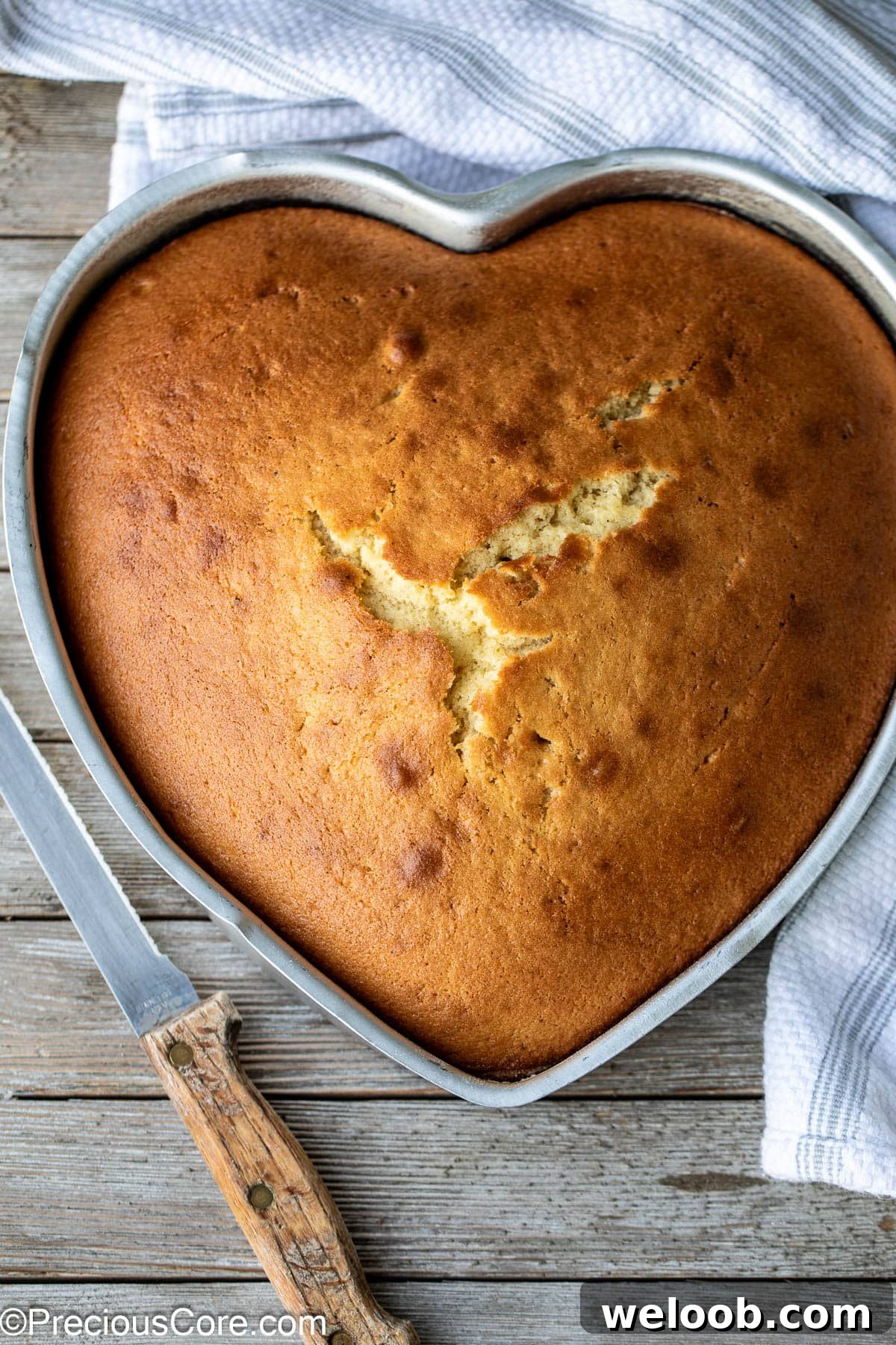 Plain cake in a heart-shaped pan with a knife on the side.