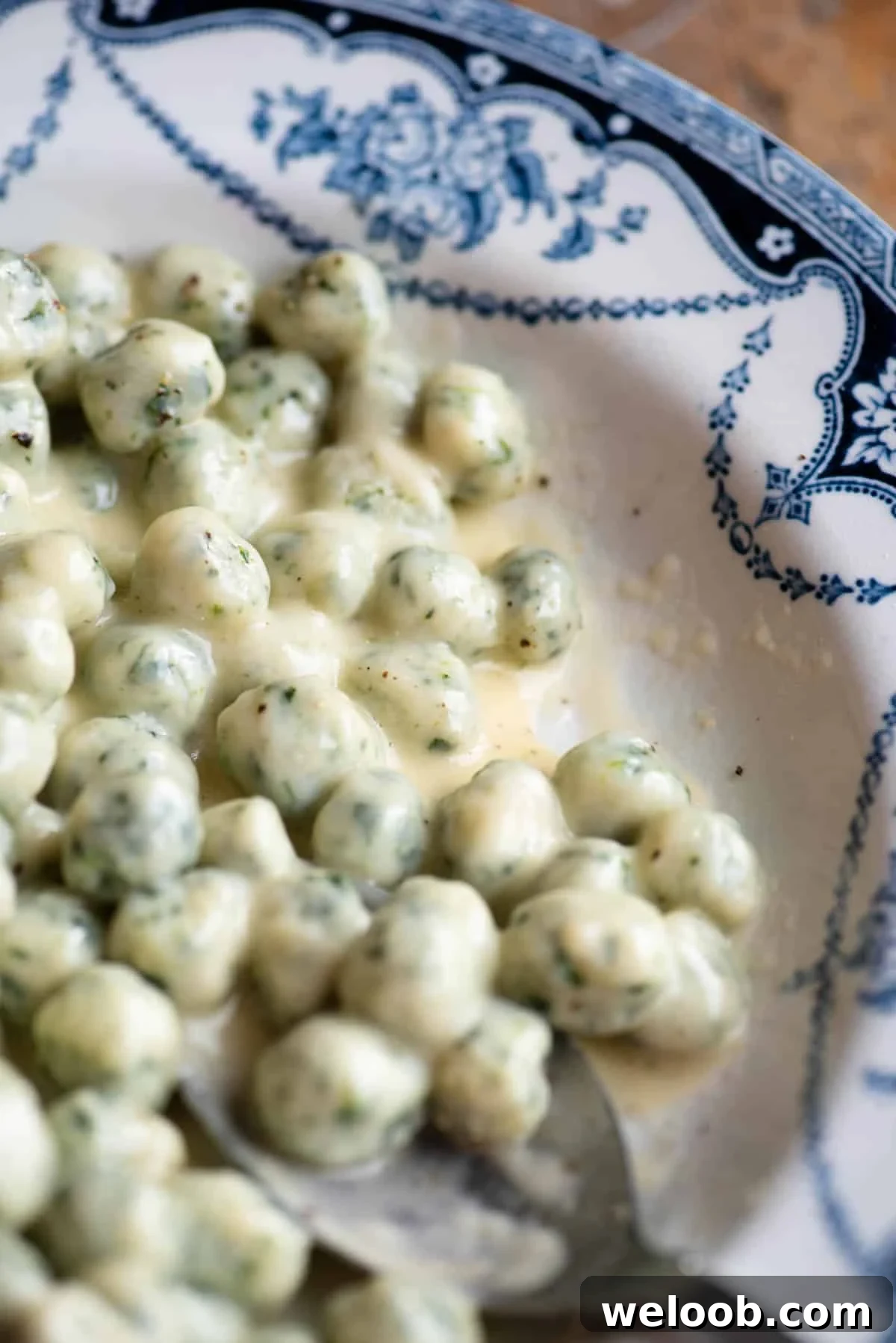 A close up of mini spinach and potato gnocchi with a creamy butter and parmigiano sauce.