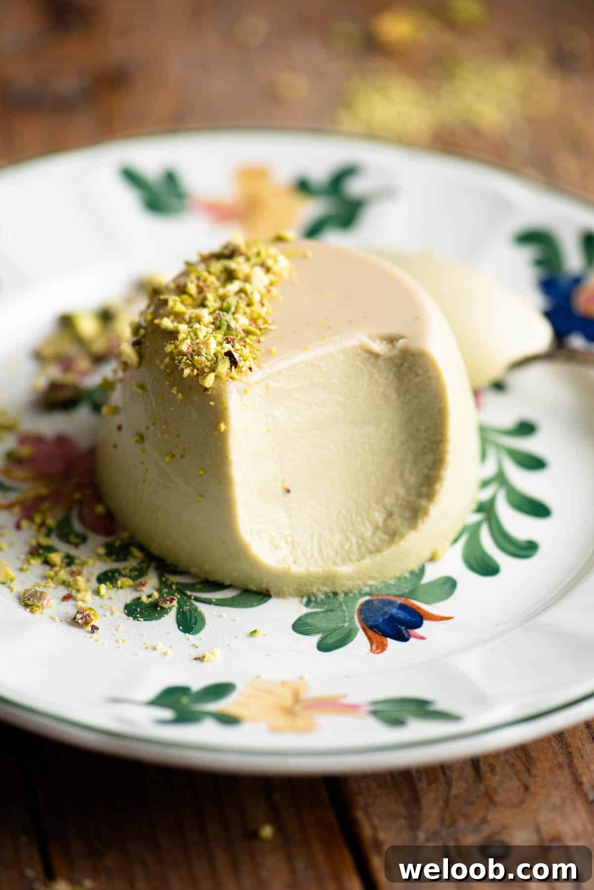 A close up of a pistachio panna cotta with a bite out to show the creamy inside.