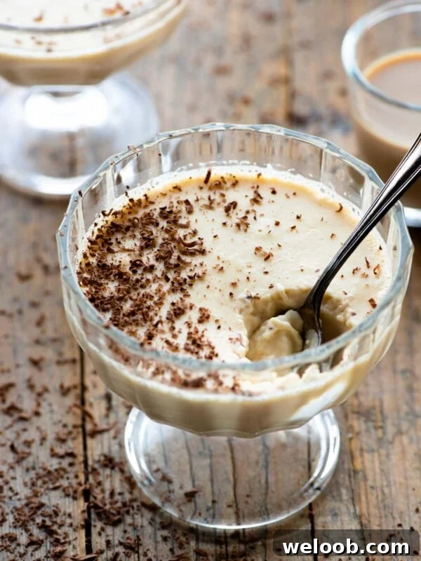 Baileys panna cotta in a small glass dish with a spoon and grated chocolate on top