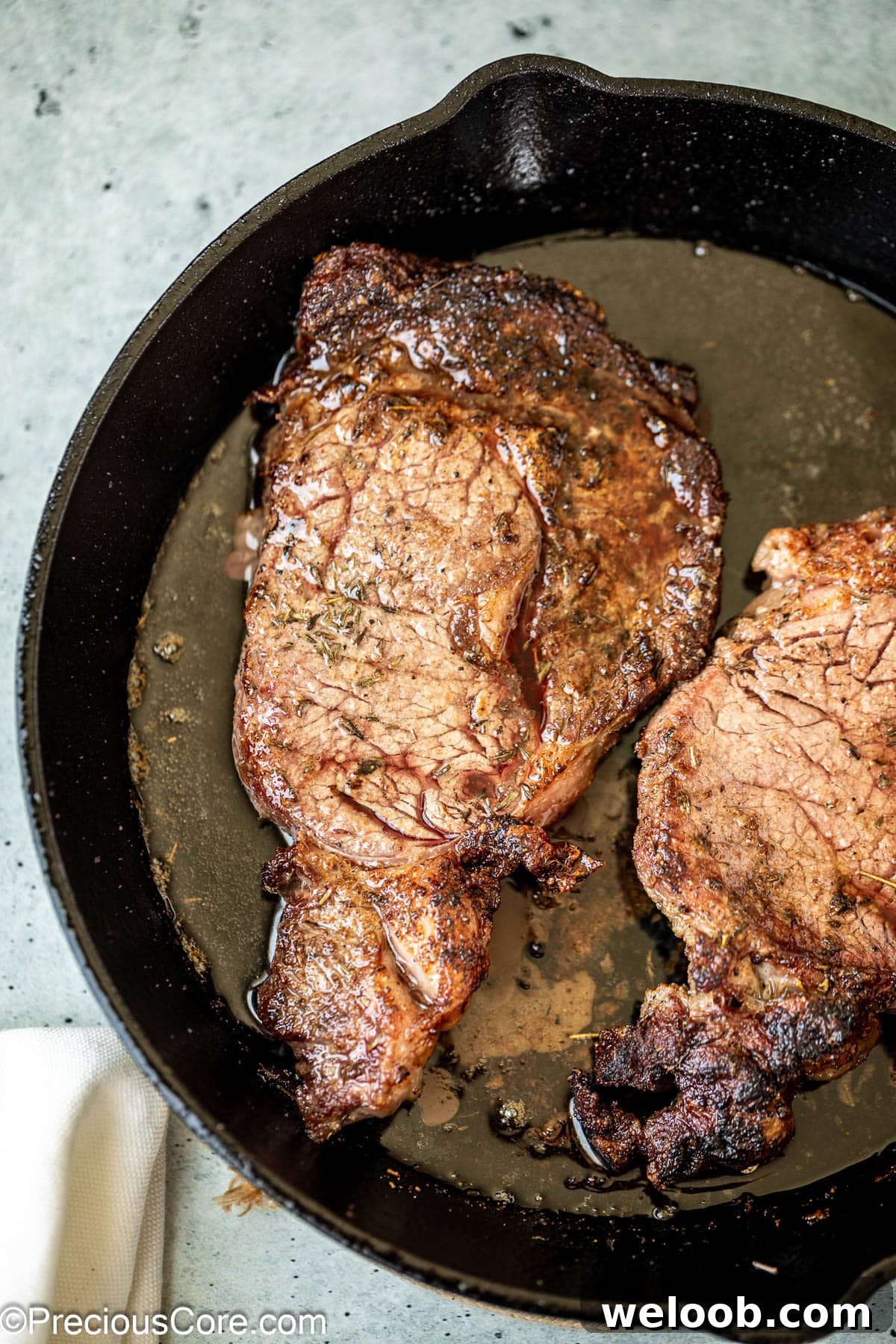 Cooking ribeye steaks in a skillet.