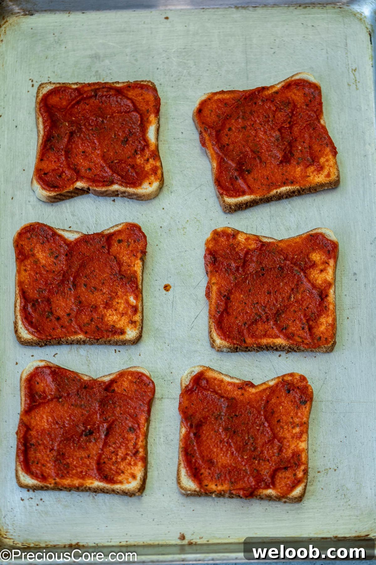 Pizza sauce spread on bread slices.