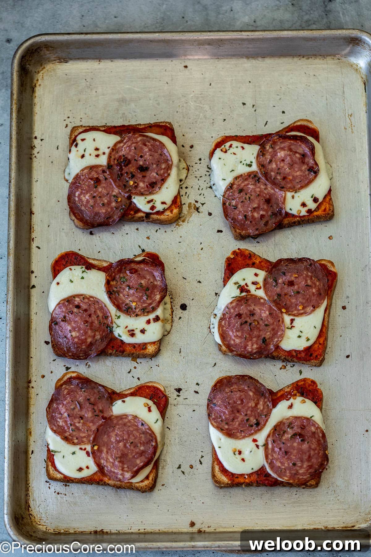 Baked pizza toasts on baking sheet.