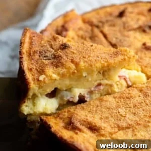 A close up of a slice of potato cake stuffed with cheese and ham.