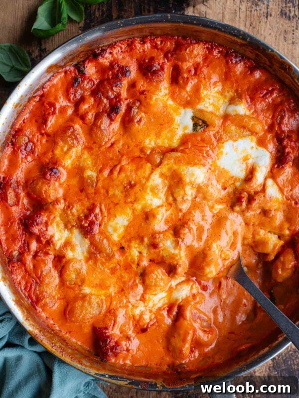 Creamy Sausage Ragu Gnocchi Recipe for Comfort Dinner 7 An overhead shot of spicy and creamy baked gnocchi in a skillet pan sitting on a wooden surface.