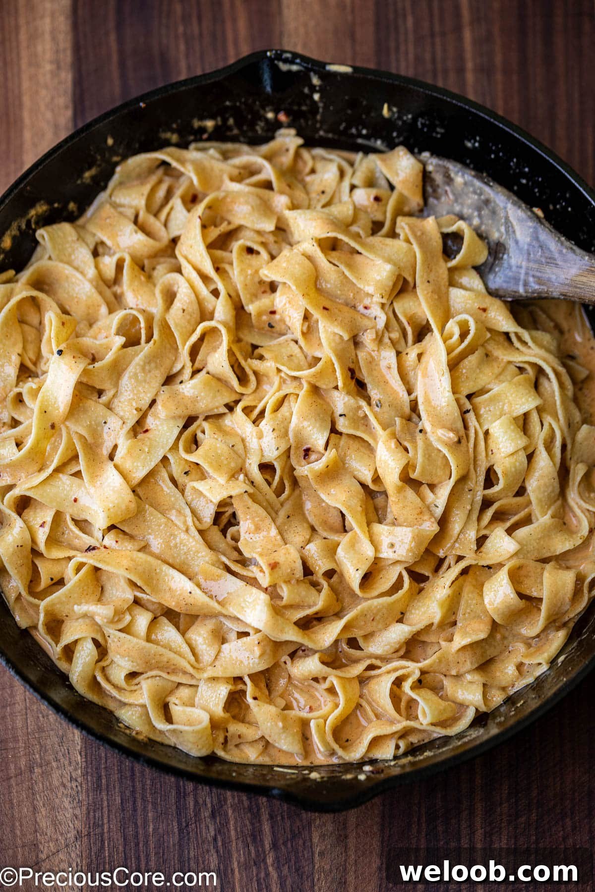 Mixing cooked pasta with homemade sauce.