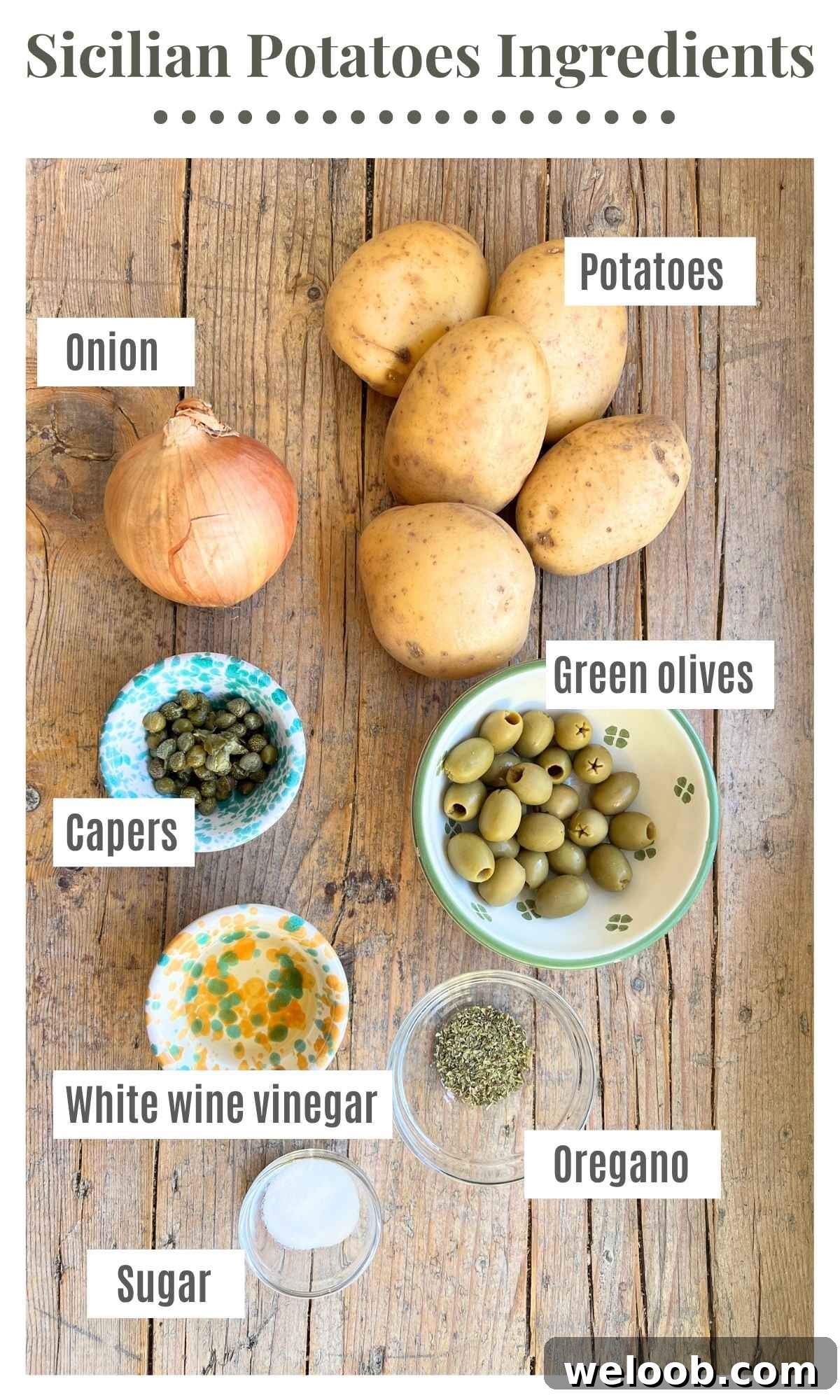 An overhead shot of all the ingredients needed to make a Sicilian potato side dish. Laid out are potatoes, onions, olives, capers, vinegar, sugar and oregano.