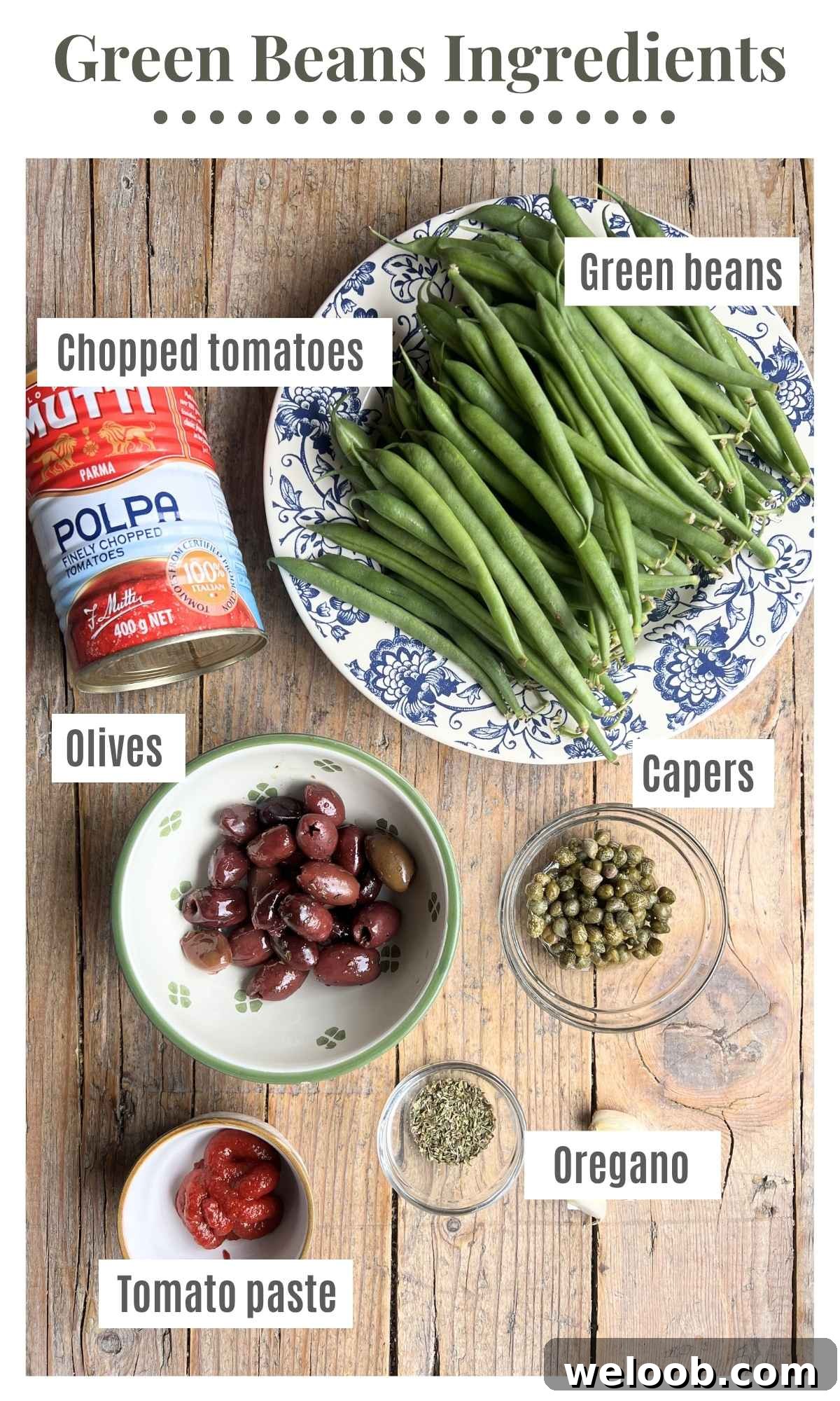 Canned tomatoes, green beans, olives, capers, oregano and tomato paste laying out on a rustic wooden board.