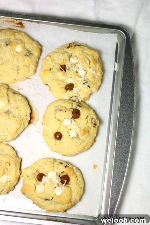 Coconut chocolate chip cookies on a lined baking sheet.