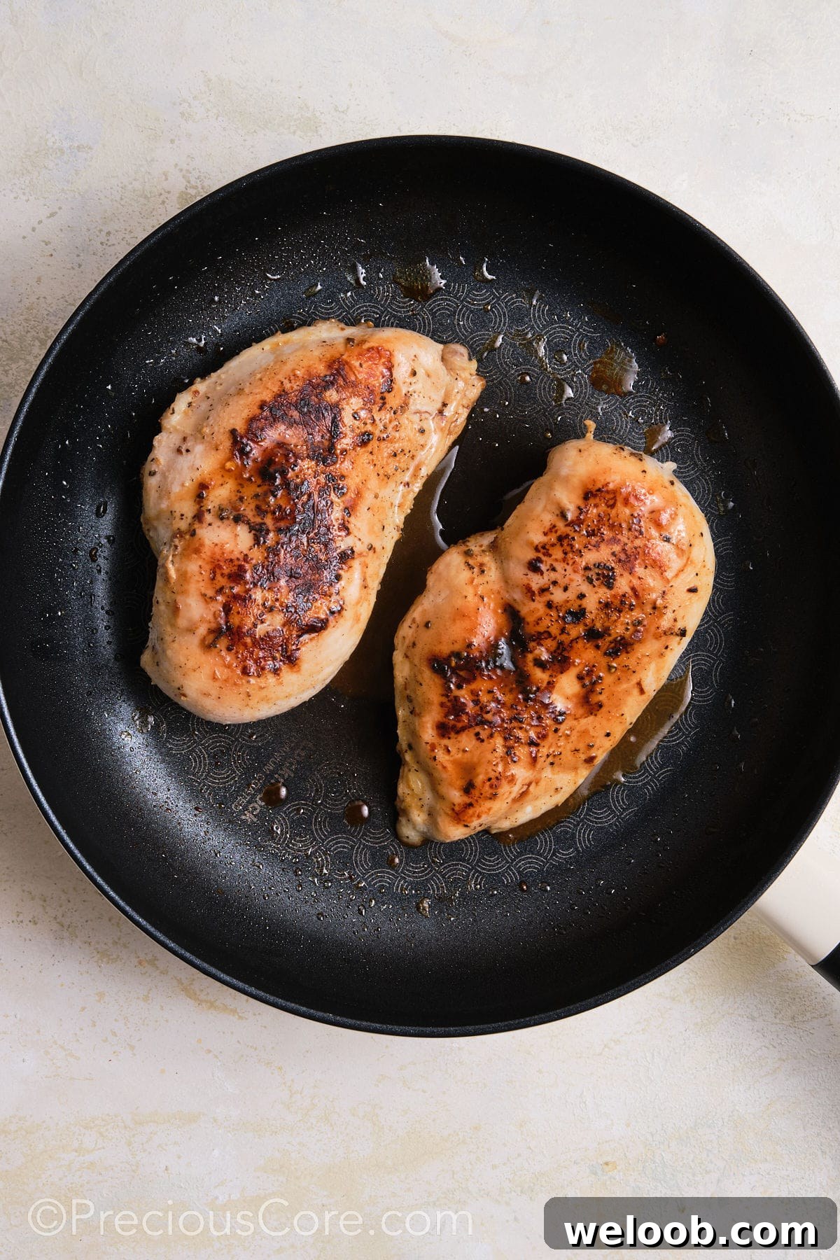Searing chicken breasts in a skillet.
