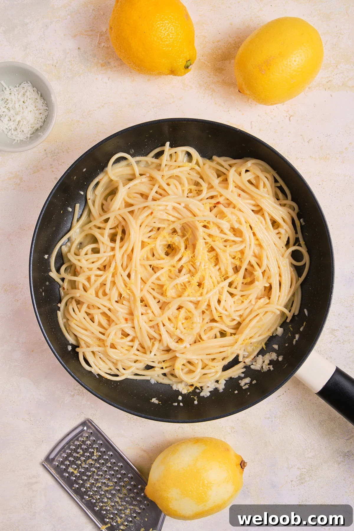Lemon zest added to a pan of pasta.