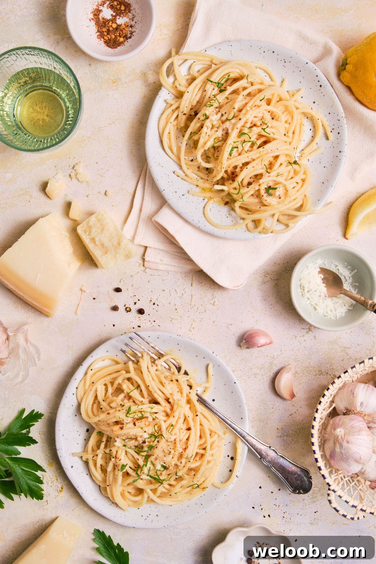 Two plates of pasta topped with grated parmesan.